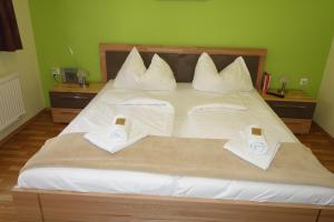 ein großes Bett mit weißen Kissen und zwei Telefonen darauf in der Unterkunft Erbhof Wegleitner in Illmitz