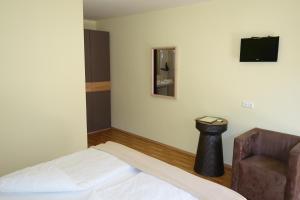 a room with a bed and a chair and a television at Erbhof Wegleitner in Illmitz