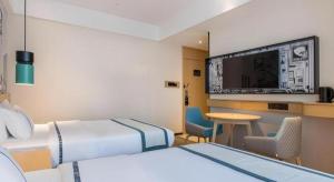 a hotel room with two beds and a flat screen tv at City Comfort Inn Ji'an South Administrative Center in Ji'an +162 photos
