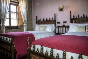 two beds in a bedroom with purple sheets at Alén do Mis - Hotel Rural in Foz