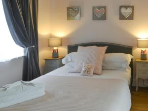 a bedroom with a bed with white sheets and hearts on the wall at Bluebell Cottage in Alnwick +9 photos