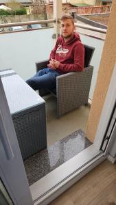 Ein Mann sitzt auf einem Korbstuhl auf einer Veranda. in der Unterkunft Kutter - ABC200 in Wismar