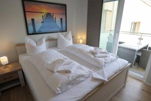 ein weißes Bett mit weißer Bettwäsche und Kissen darauf in der Unterkunft Kutter - ABC200 in Wismar