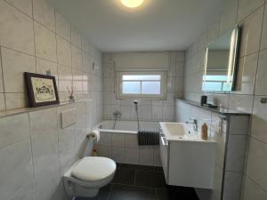 a white bathroom with a toilet and a sink at Ferienhaus "De lütten Tieden" 65358 in Moormerland +7 photos