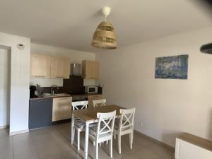 une cuisine avec une table et des chaises dans une pièce dans l'établissement Les Jasmins, à La Croix-Valmer