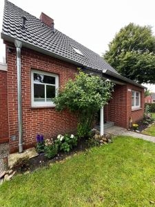a small red brick house with a window at Ferienhaus "De lütten Tieden" 65358 in Moormerland