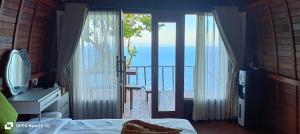 a bedroom with a door open to a balcony at The Indah Cliff Sea View in Polilit