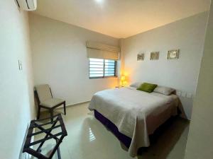 a bedroom with a bed and a chair and a window at Charming Condo in Gaviotas Walk to Beach cafes, restaurants within Golden Zone in Mazatlán