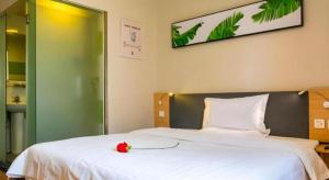 a bedroom with a white bed with a red flower on it at 7 Days Inn Urumqi Guangming Road Beimen Metro Station in Ürümqi