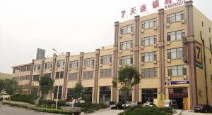 a large building with cars parked in front of it at 7 Days Inn Qingdao Haier Zone Ditie Tower Jiushui West Road in Qingdao