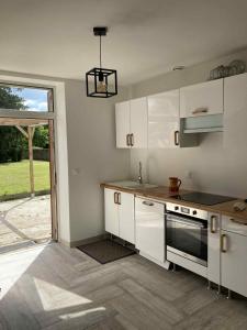 a kitchen with white cabinets and a stove top oven at Maison du bonheur spa in Neuvic