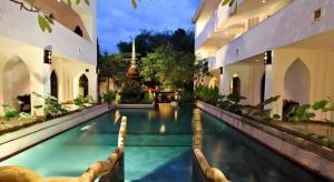 a swimming pool in a courtyard of a building at Gudi Boutique Resort in Mae Rim