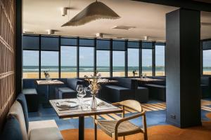 a restaurant with tables and chairs and a view of the beach at Atlantic Hôtel & Spa in Les Sables-d'Olonne