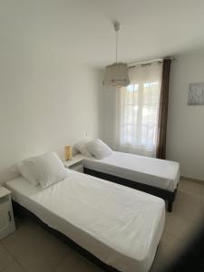 une chambre avec deux lits et une fenêtre dans l'établissement Les Jasmins, à La Croix-Valmer 14 autres photos