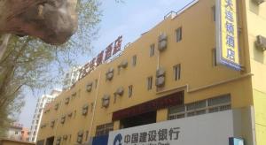 ein gelbes Gebäude mit einem Schild davor in der Unterkunft 7 Days Inn Yantai Dahaiyang Raod Railway Station in Yantai