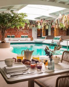 a table with a tray of food next to a swimming pool at Atlantic Hôtel & Spa in Les Sables-d'Olonne