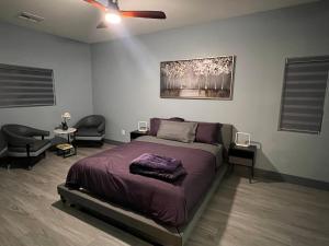 a bedroom with a bed with two chairs and a ceiling fan at Family Friendly Contemporary House with Pool in Las Vegas +30 photos