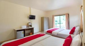 une chambre d'hôtel avec deux lits et une télévision dans l'établissement OYO 75359 Thaiburi Thara Resort, à Ban Yan Chao