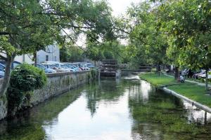 Un río con coches aparcados a un lado. en Colombe, en LʼIsle-sur-la-Sorgue