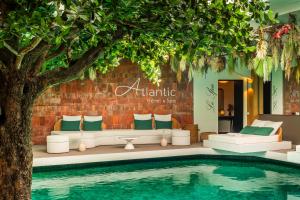 a swimming pool with a couch and a tree at Atlantic Hôtel & Spa in Les Sables-d'Olonne