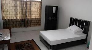 a bedroom with a white bed and a desk and window at Hotel O Jahip Syariah in Bojong Dua