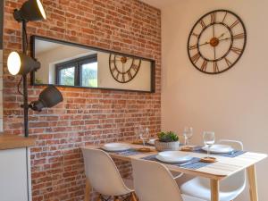 a dining room with a table and a clock on the wall at River Lodge Annexe in Rhondda