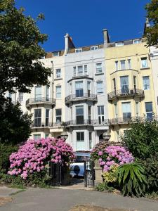 a large building with pink flowers in front of it at Sea Spray Victorian Apartment in St. Leonards