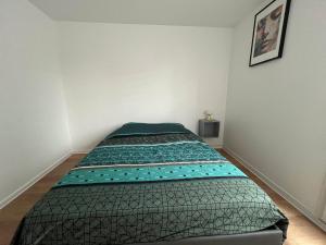 a bed in a room with a green comforter at PERLE HDG Tout Confort in La Courneuve
