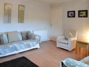 a living room with a couch and two chairs at Honey Cottage in Auchnarrow