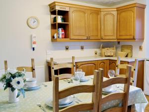 a kitchen with a table with chairs and a clock on the wall at Honey Cottage in Auchnarrow