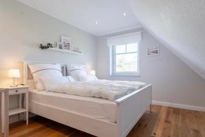 a white bedroom with a bed and a window at Reethaus MeerFerien direkt am Wasser in Mellnitz