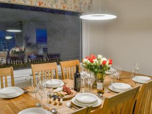 a dining room table with plates and flowers and a window at Balnacraig in North Kessock