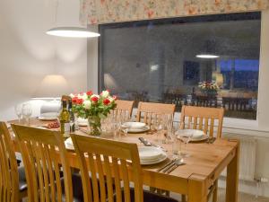a wooden table with chairs and a table with flowers on it at Balnacraig in North Kessock +20 photos