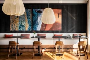 a bar with stools and a painting on the wall at Hotel & Spa Les Roches Noires in Les Sables-d'Olonne