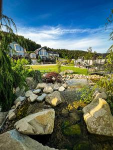 a pond with rocks in a yard with houses at Dream Hill - Dom Premium z jacuzzi oraz sauną w cenie i na wyłączność in Jazowsko