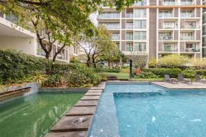 a swimming pool in front of a large building at The Nimmana Condo 410 - Super Deluxe 1BR Balcony extension in Chiang Mai