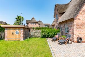 un patio trasero con una casa de ladrillo y una valla en FriesenLodge, en Utersum