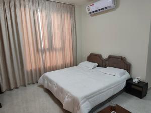 a bedroom with a bed and a large window at بناية الكورنيش in Mirbāţ