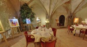 a dining room with tables and chairs and paintings at Logis Hotel de Paris in Saint-Avold