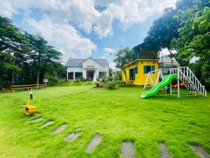 a large yard with a playground with a yellow house at LaLi Home in Hanoi