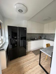 a kitchen with a black refrigerator and white cabinets at Magiczny apartament in Duszniki Zdrój