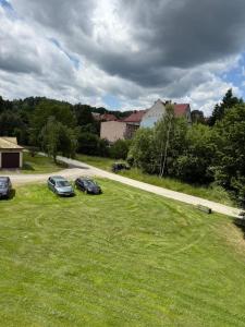 two cars parked in a field next to a road at Magiczny apartament in Duszniki Zdrój