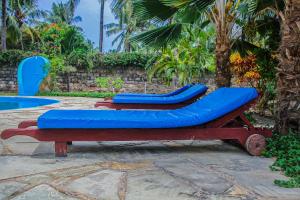two blue chairs sitting next to a pool at Diani Villa in Gatunga