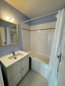 ein Badezimmer mit Waschbecken, Badewanne und Spiegel in der Unterkunft Maison à 5 min de Disneyland Paris in Esbly