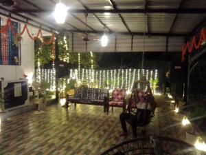 a woman sitting in a chair in a room with lights at La Goodwill Garden Luxury villa in Auroville