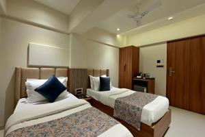 una camera d'albergo con due letti con cuscini blu di Hotel Kalpana Palace, Mumbai a Mumbai