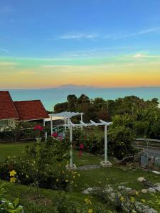 a white pergola in a yard with a view of the ocean at VELAMUNDi INN Batu Ferringhi in Batu Ferringhi +24 photos