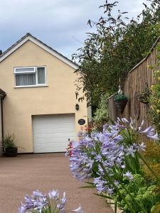 a house with a garage and purple flowers at The Loft at Pen Orchard in Winscombe