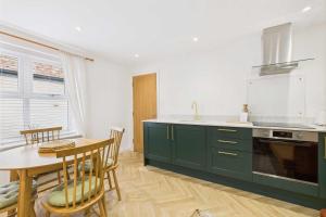 une cuisine avec des armoires vertes et une table et une salle à manger dans l'établissement Host & Stay - Bracken Cottage, à Stokesley