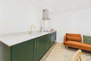 une cuisine avec des armoires vertes et une chaise marron dans l'établissement Host & Stay - Bracken Cottage, à Stokesley